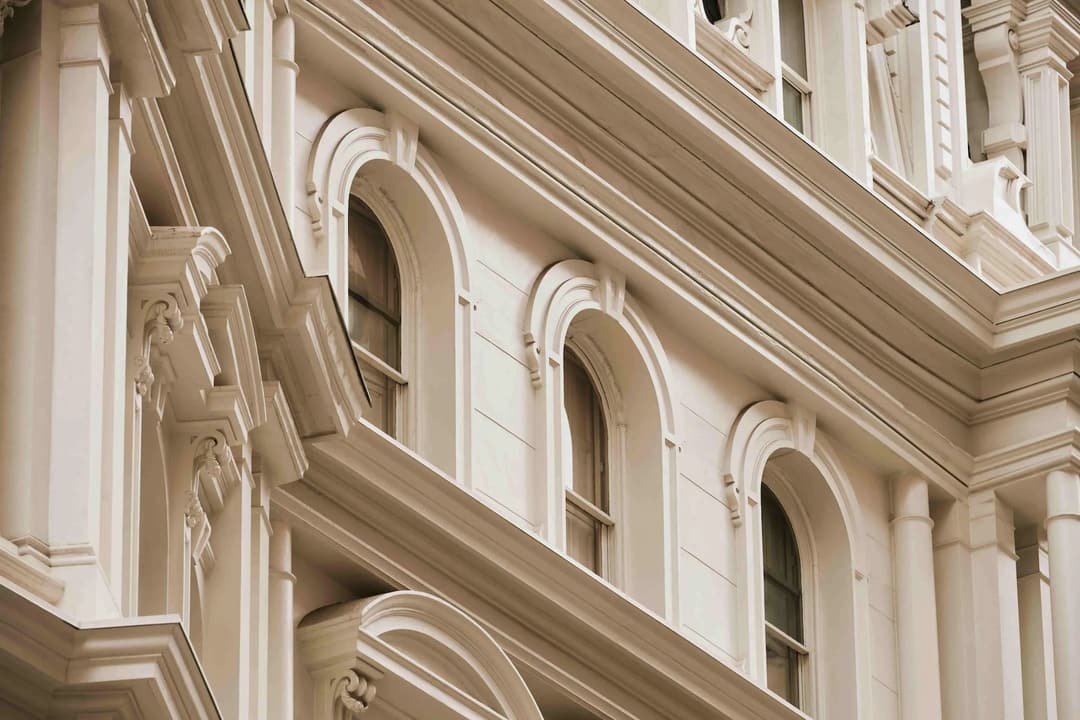 Ornate cornices and arched windows on a stone facade at The Fifth Avenue Hotel