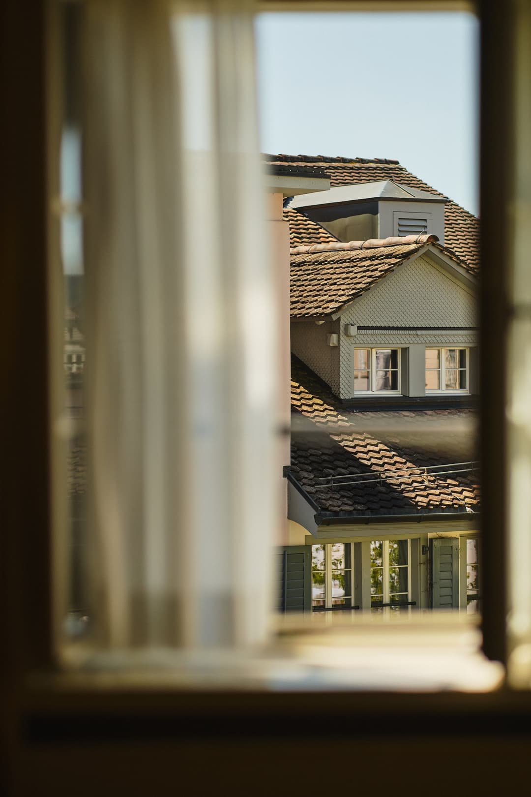 Window framing a view of tiled rooftops at Widder Hotel, Zurich