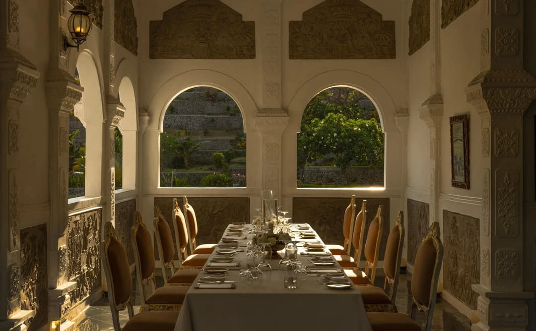 Royal dinner setup at Amankila, Karangasem, with candlelit table beneath arched pavilion overlooking gardens