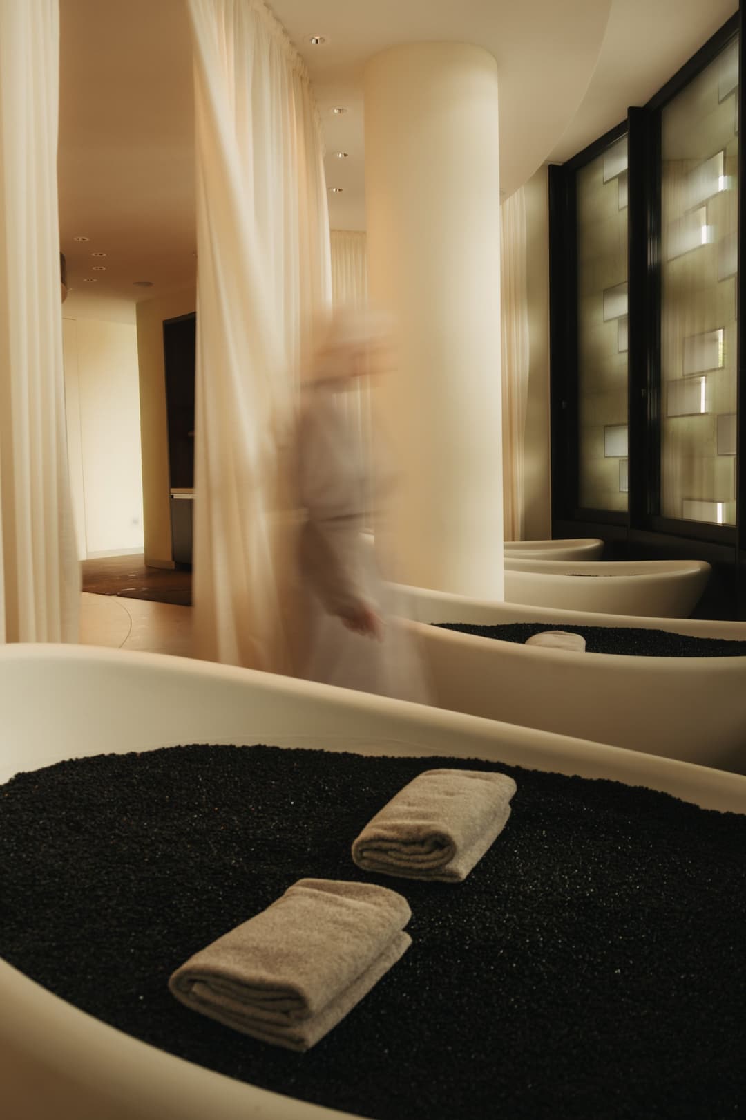 Soaking tubs filled with black pebbles and folded grey towels at The Dolder Grand