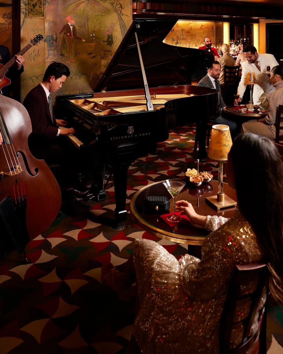 Piano and double bass in a bar with painted mural walls at The Carlyle