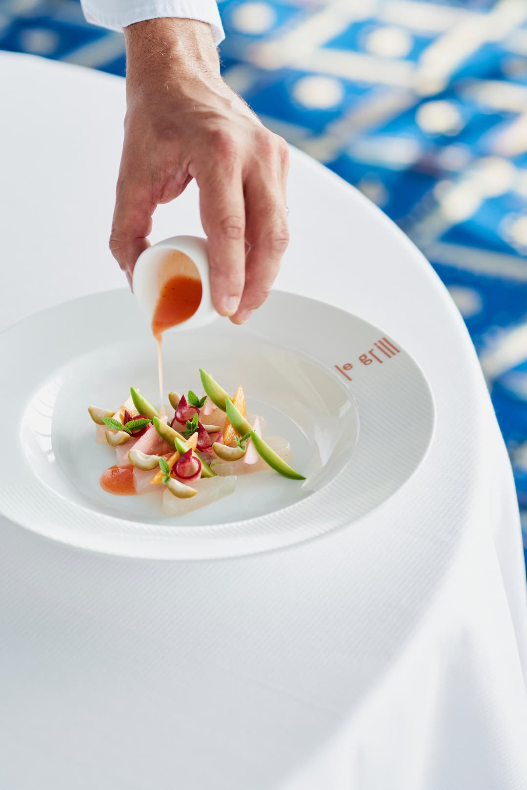 Chef pouring sauce over a plated dish at Hotel De Paris Monte Carlo
