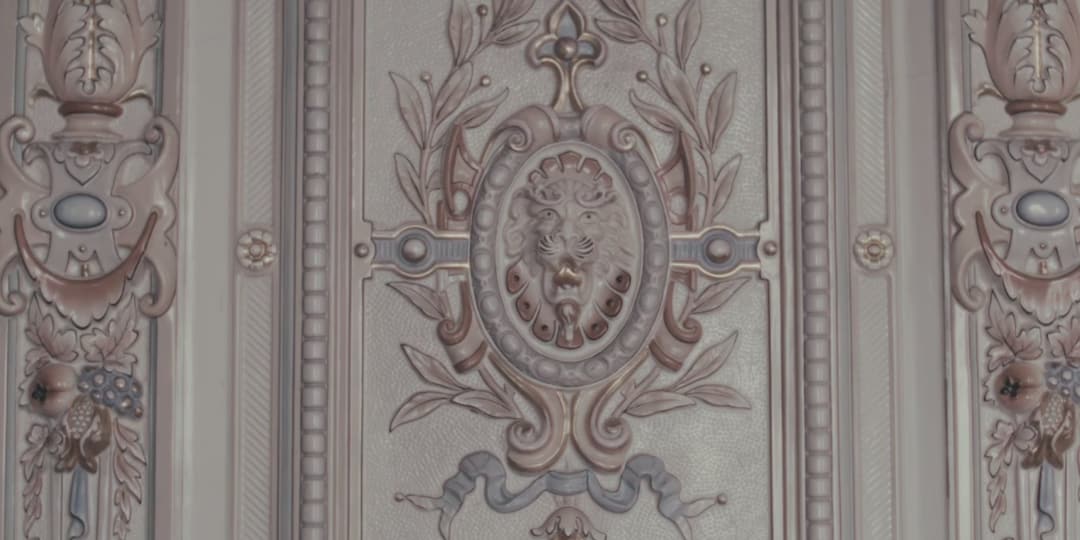 Ornate plaster relief with a lion mask on a wall at Hotel Haven