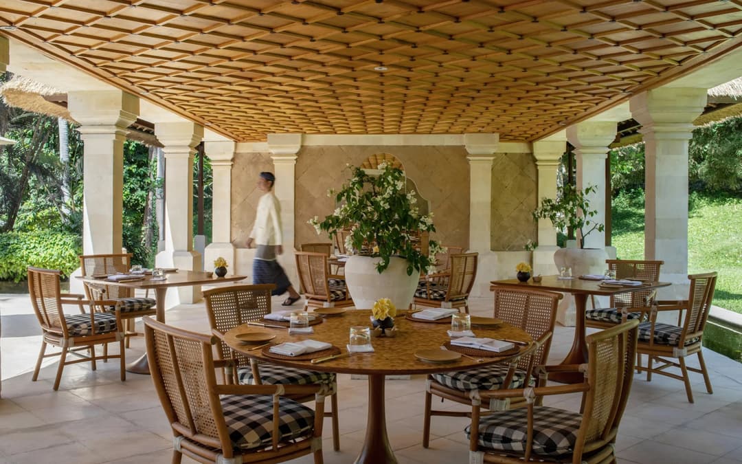 Amankila's beachclub restaurant pavilion with wooden ceiling, dining tables and woven chairs overlooking gardens