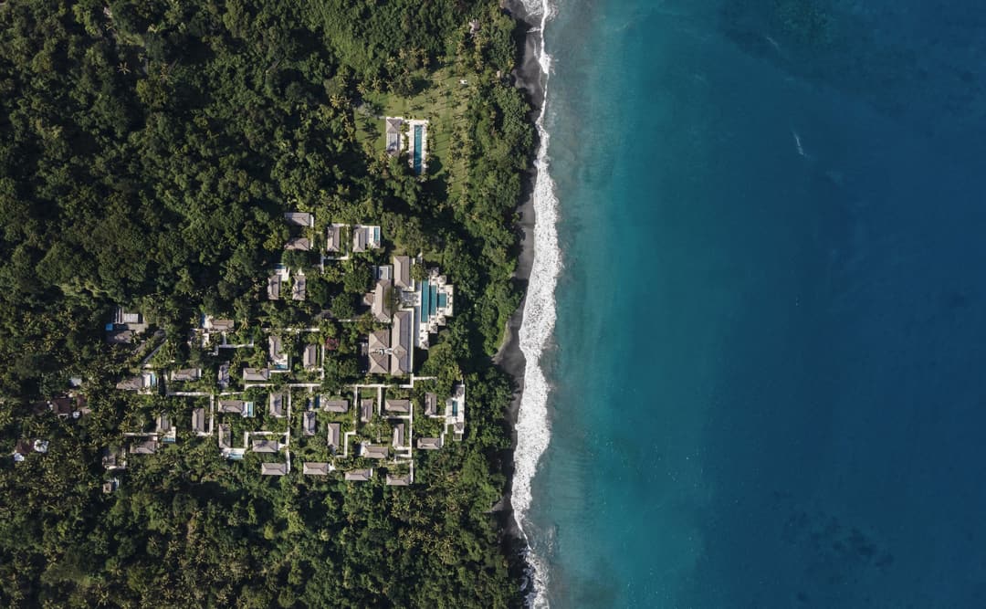 Aerial view of Amankila's coastal landscape with forested hillside meeting turquoise waters, Manggis (East Bali)