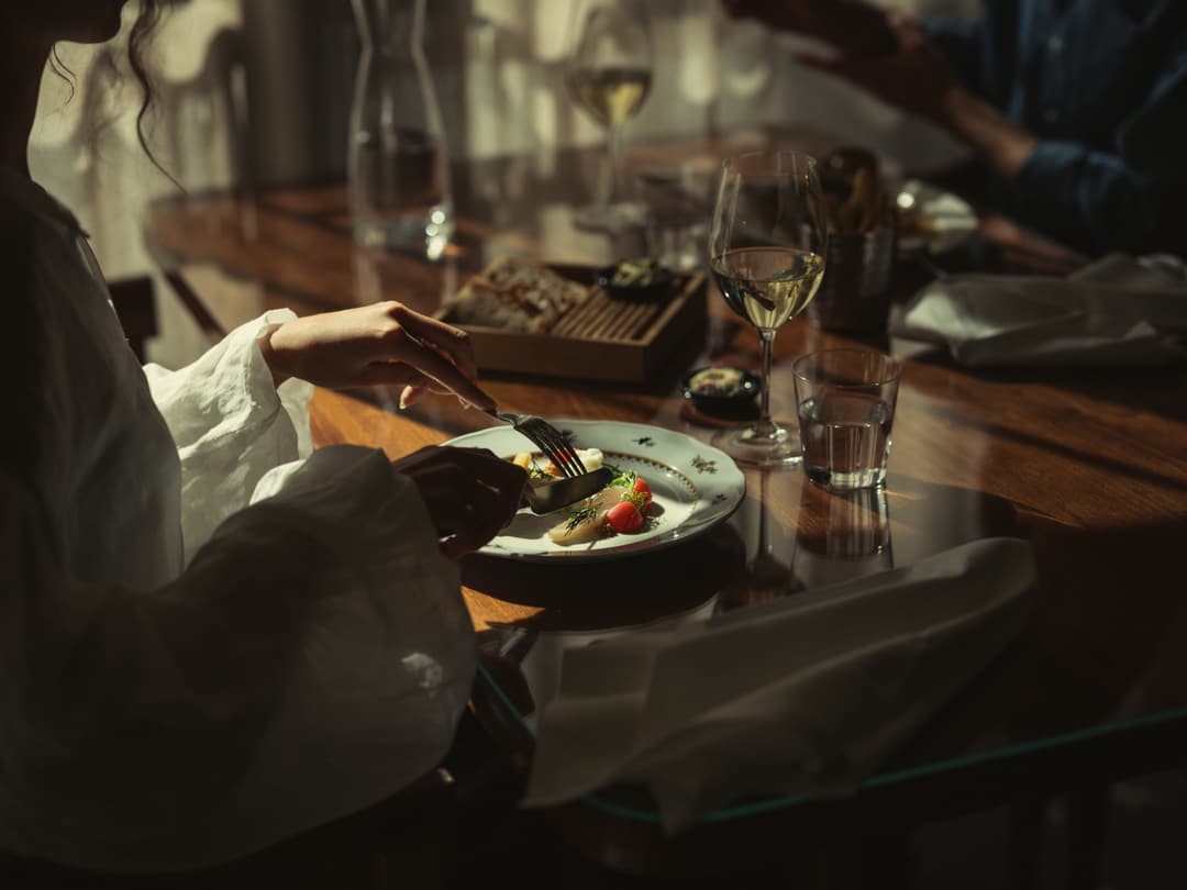 Plated dish with strawberries and herbs beside a glass of white wine at Hotel Kämp