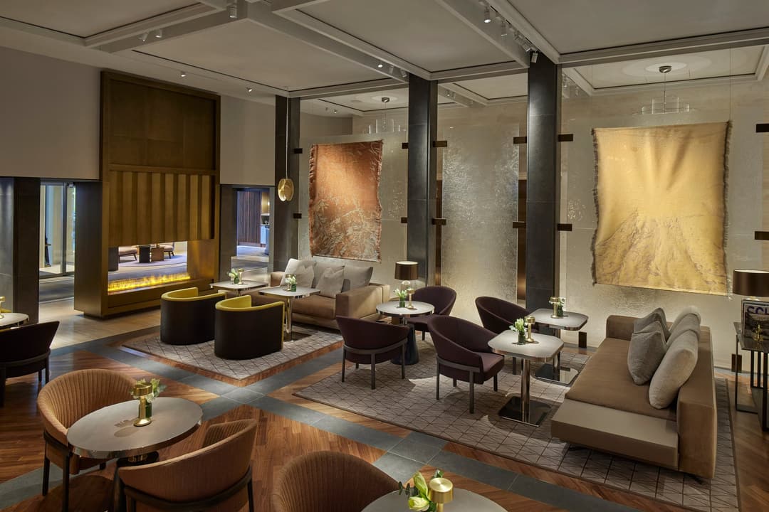Lounge with a fireplace, sofas and small round tables at Mandarin Oriental Savoy, Zurich