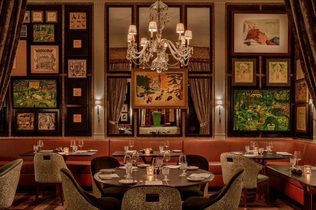 Dining room with framed artworks, red banquettes and a crystal chandelier at The Carlyle
