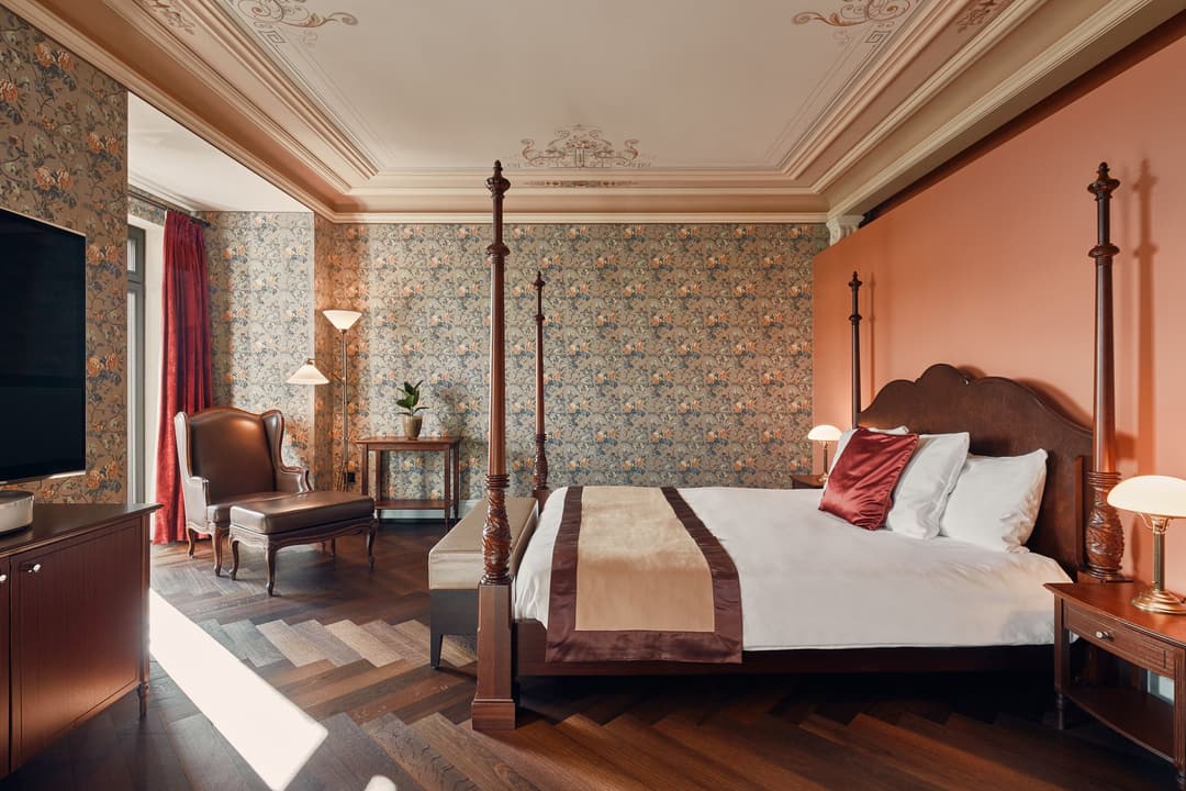 Elegantes Zimmer im Dolder Grand mit Himmelbett, dekorativer Blumentapete, Holzboden und Ledersessel