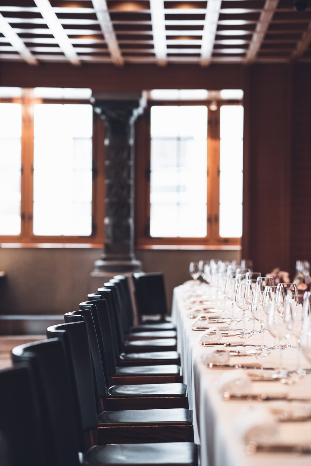 Dining room with a long table set for dinner and leather chairs at Widder Hotel, Zurich