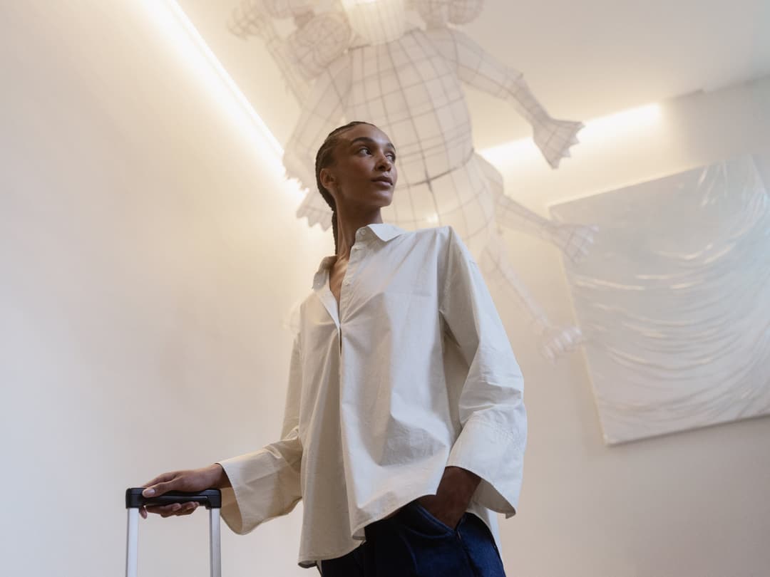 Woman with a rolling suitcase beside a wall artwork at Hotel St George, Helsinki