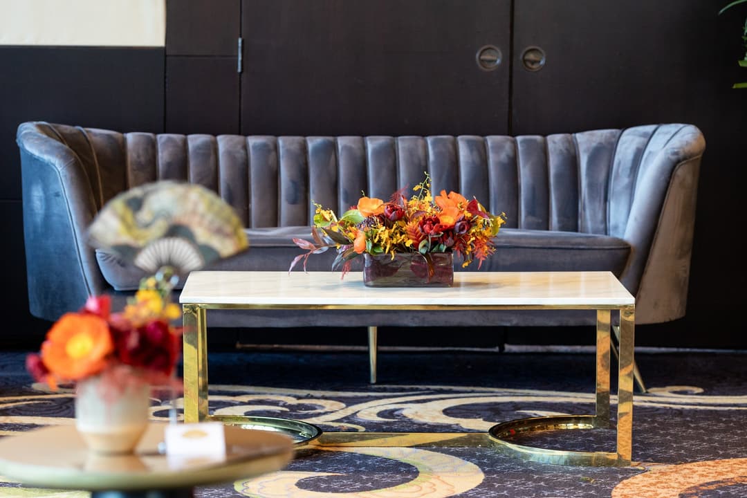 Grey velvet sofa and brass-framed coffee table with flowers at Mandarin Oriental, New York