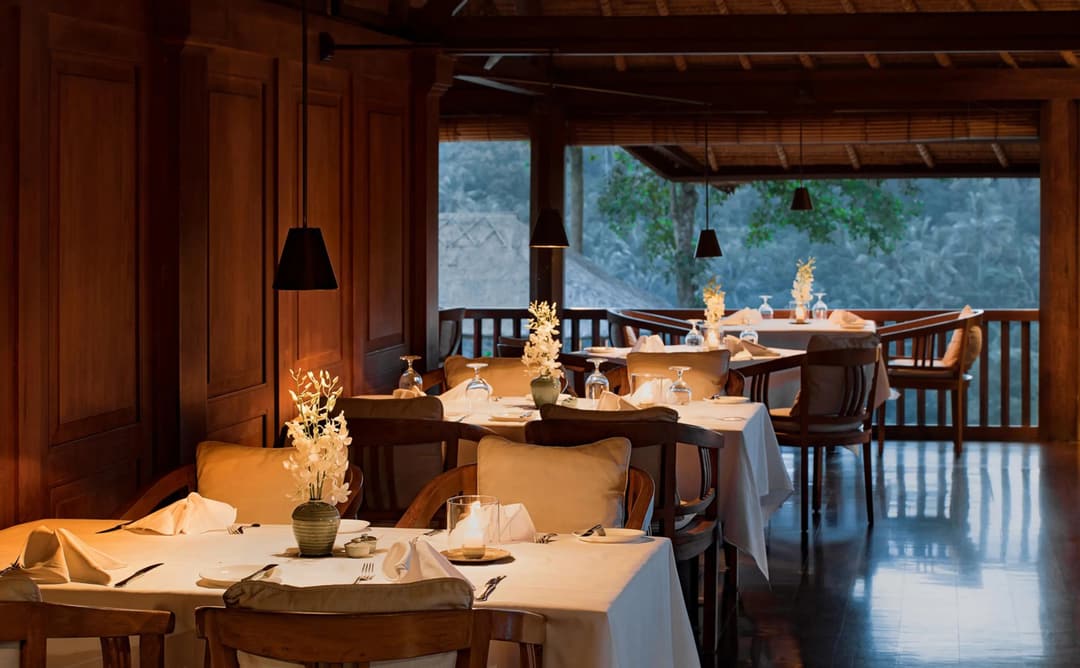 Amandari restaurant terrace at dusk, with warm-lit dining tables overlooking the Ubud valley in Bali