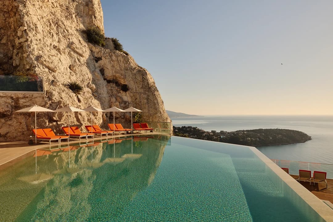 A serene swimming pool at Maybourne Riviera, featuring sleek contemporary design and expansive views over the Mediterranean coastline.