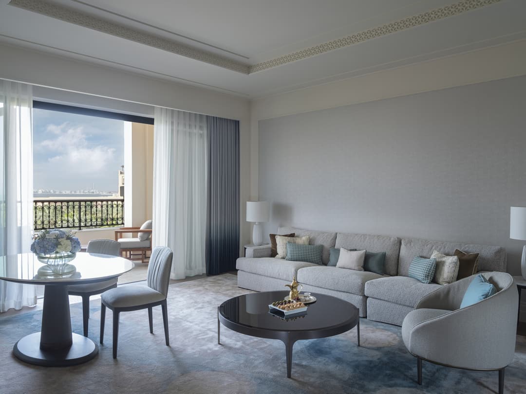 Hotel suite living room with sofa, arm chair, round table and two chairs, and a walk-out terrace, Four Seasons Resort Dubai at Jumeirah Beach