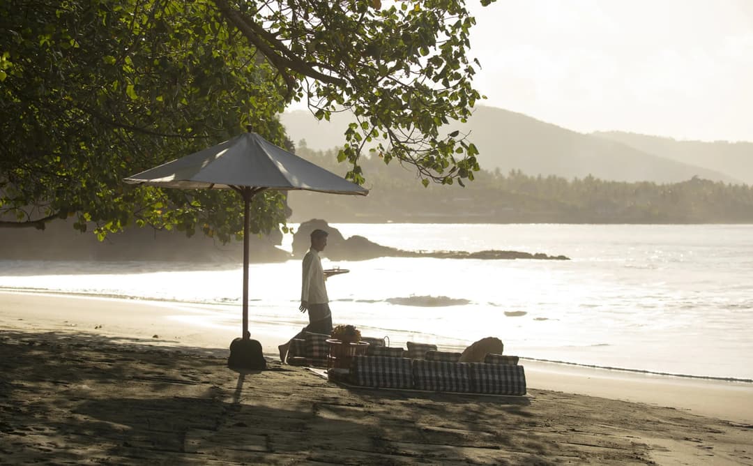 Beachside picnic setup at Amankila with umbrella and seating overlooking calm waters in Bali, Manggis (East Bali)