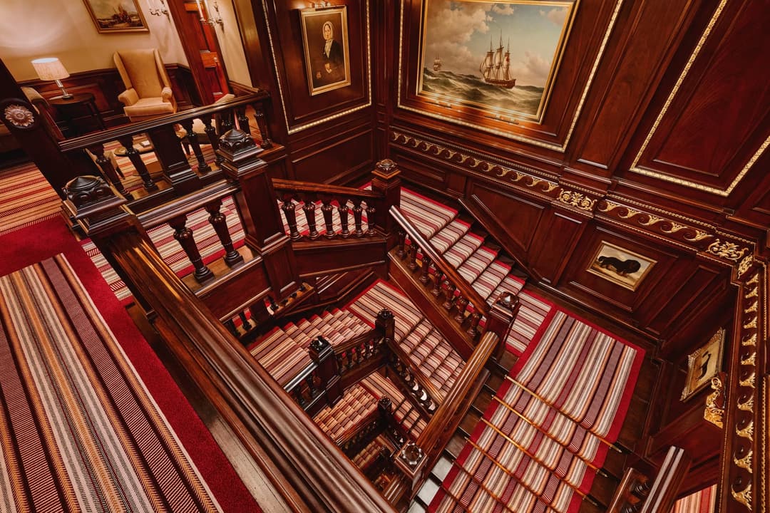 The grand staircase at The Connaught with its elegant curved banister and soft lighting, Mayfair