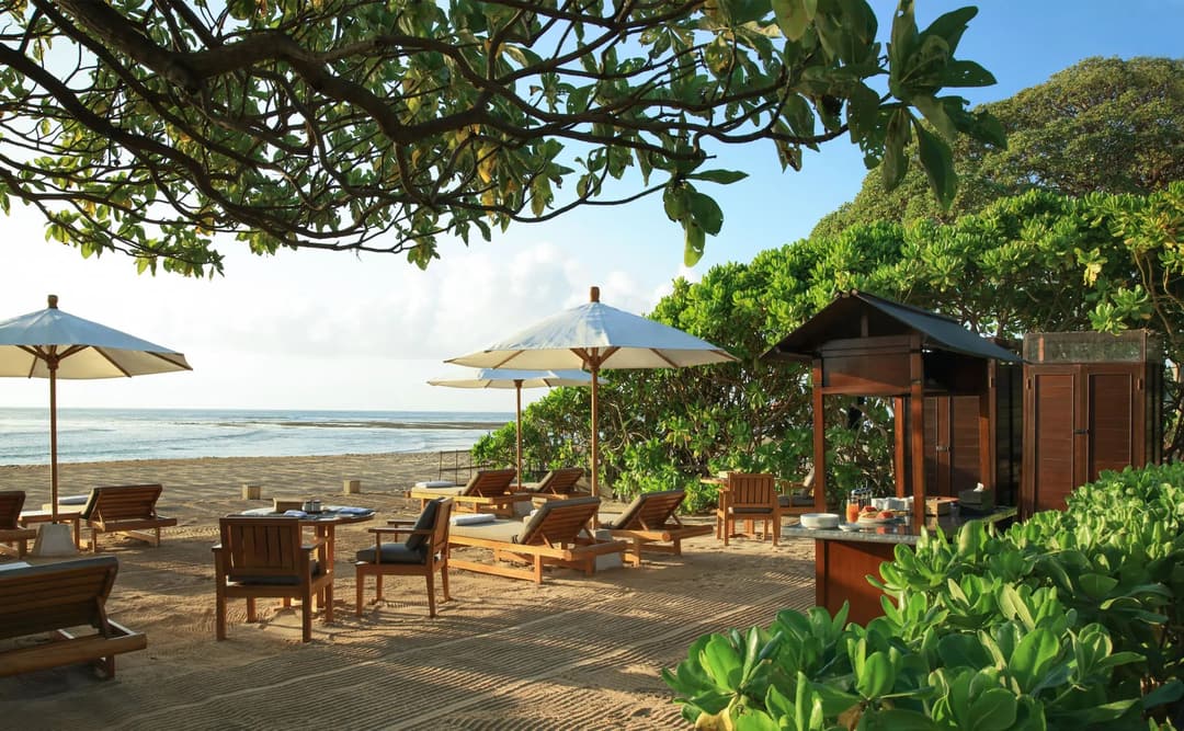 Beachfront terrace at Aman Villas at Nusa Dua with wooden loungers, tropical plants, and ocean views