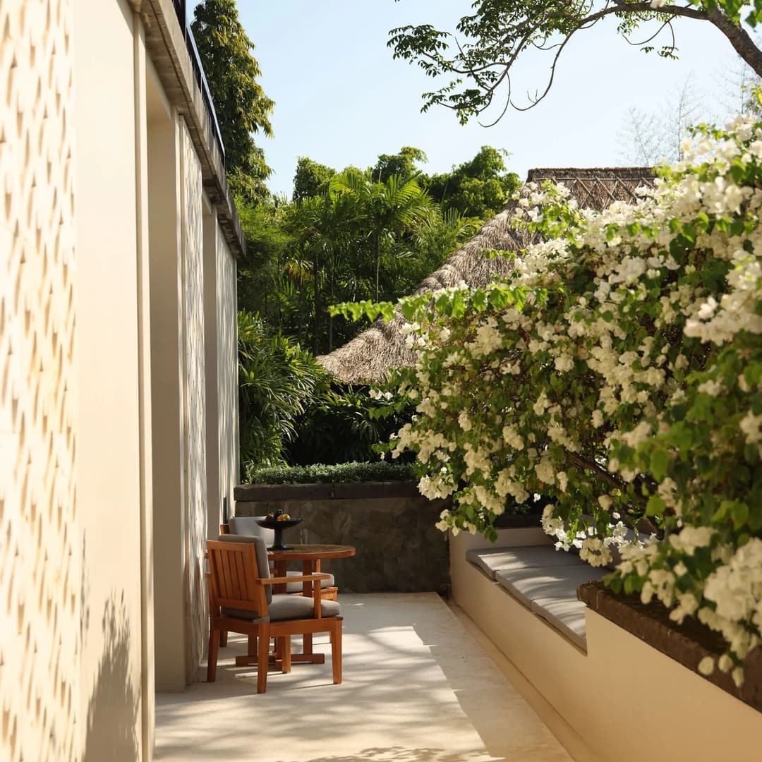 Resort terrace at Aman Villas at Nusa Dua with wooden chair and lush garden views