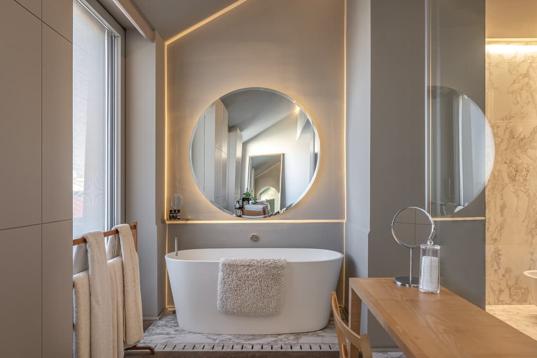 Luxury freestanding bathtub with a large backlit round mirror at Verride Santa Catarina, Verride Palacio de Santa Catarina