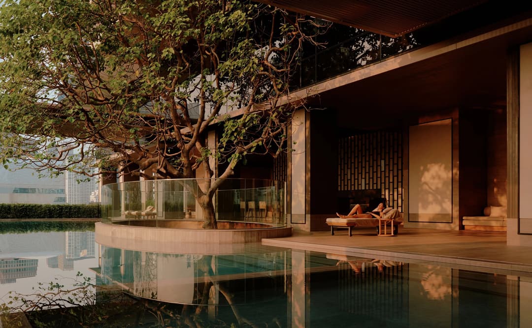 Wellness swimming pool at Aman Nai Lert Bangkok, with wooden platform beside calm water and traditional Thai architecture