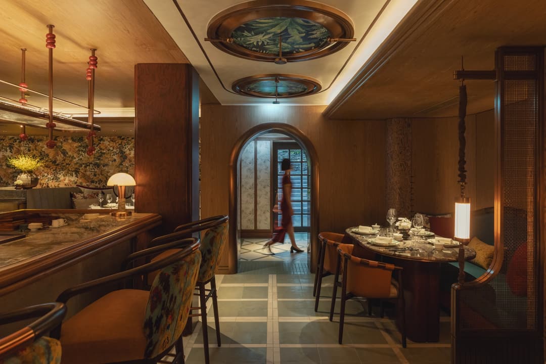 the restaurant interior with warm lighting, marble bar, and a woman walk pass the door, Mandarin Oriental Bangkok