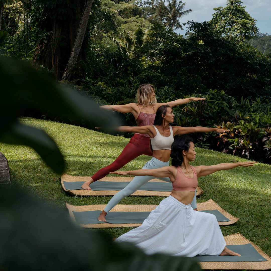 Two women practising yoga on mats in Amandari's lush garden grounds, Ubud, Bali, Ubud (Kedewatan)